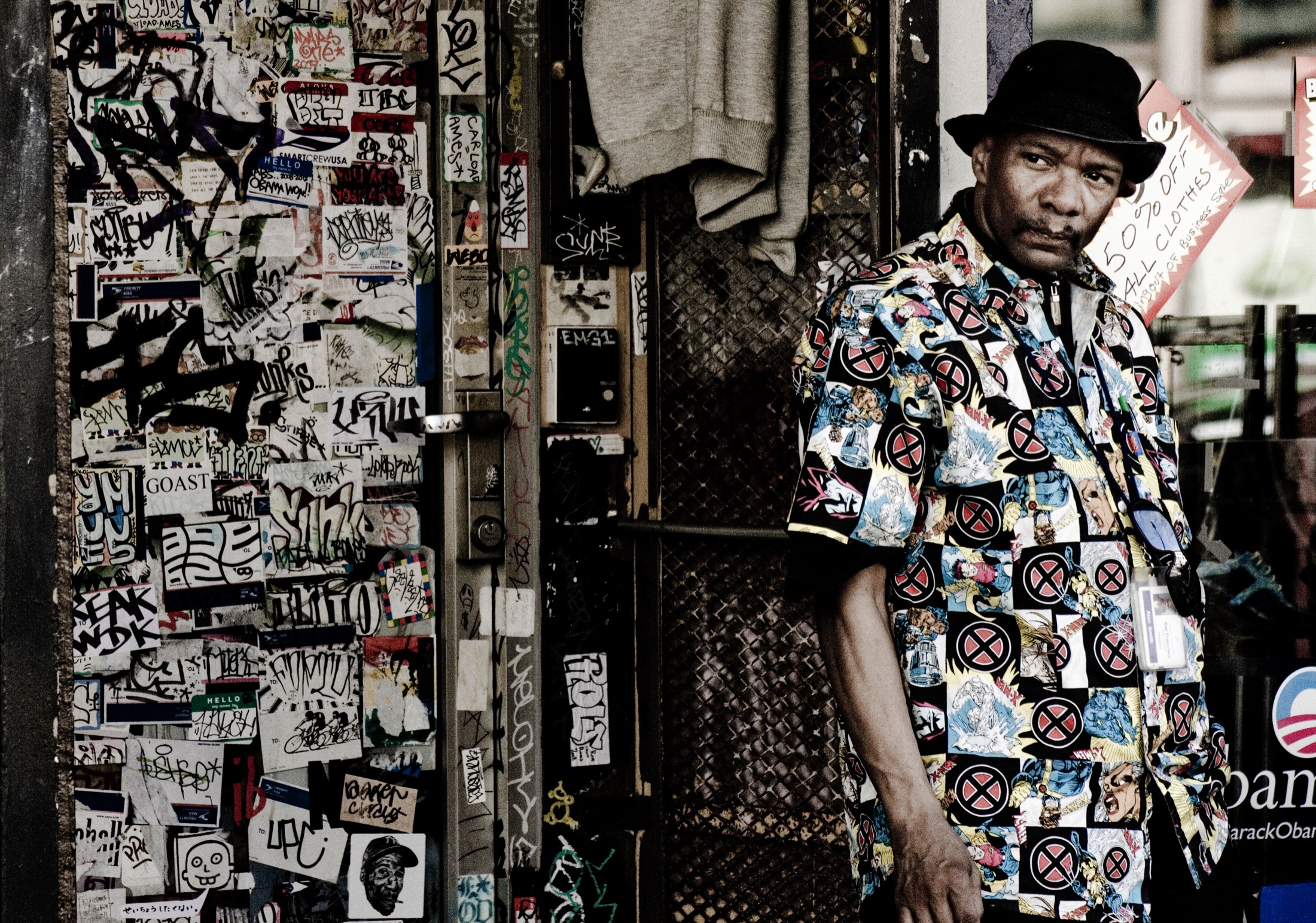 A man in a patterned shirt standing beside a layered city wall