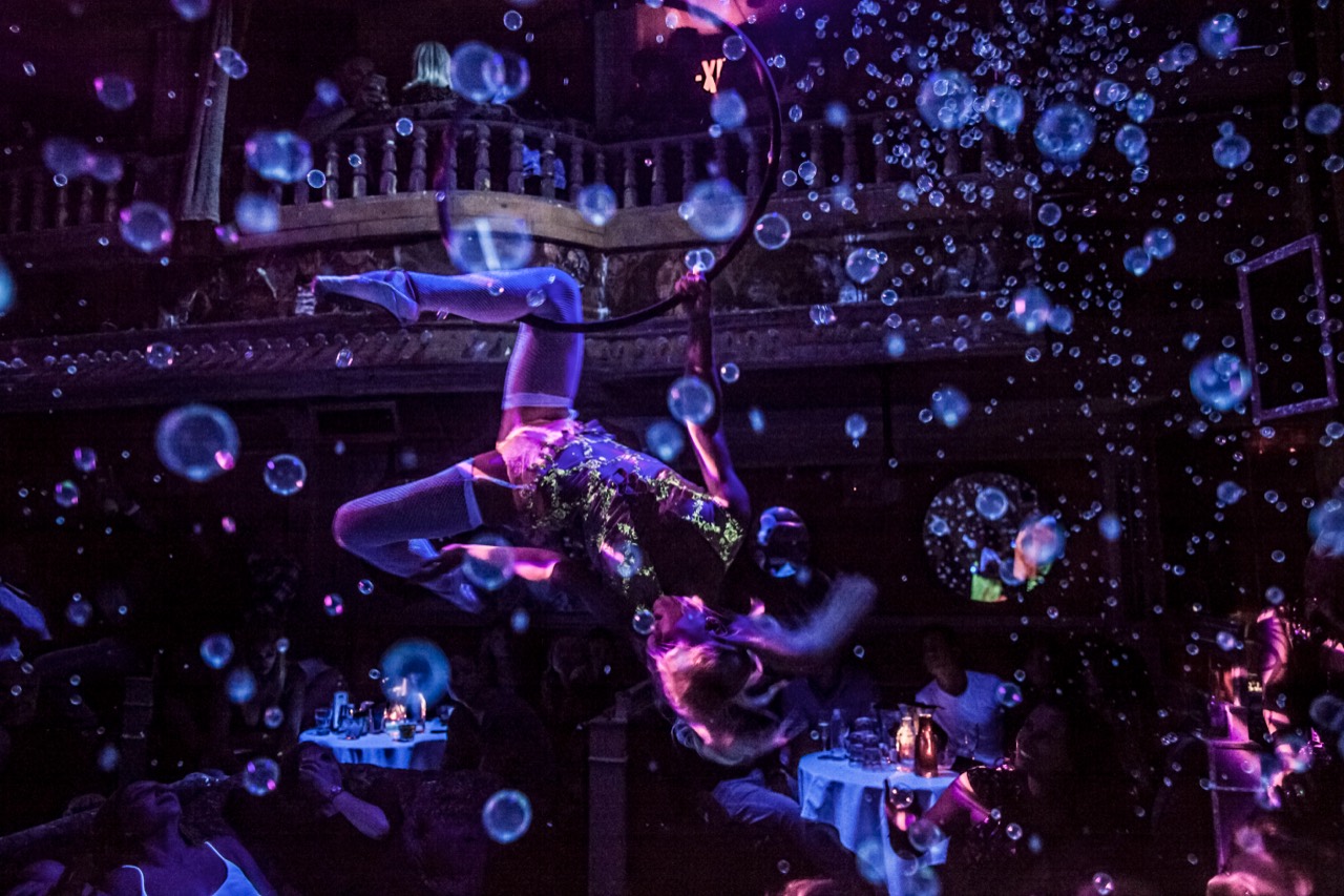 An aerial performer moving through bubbles inside The Box