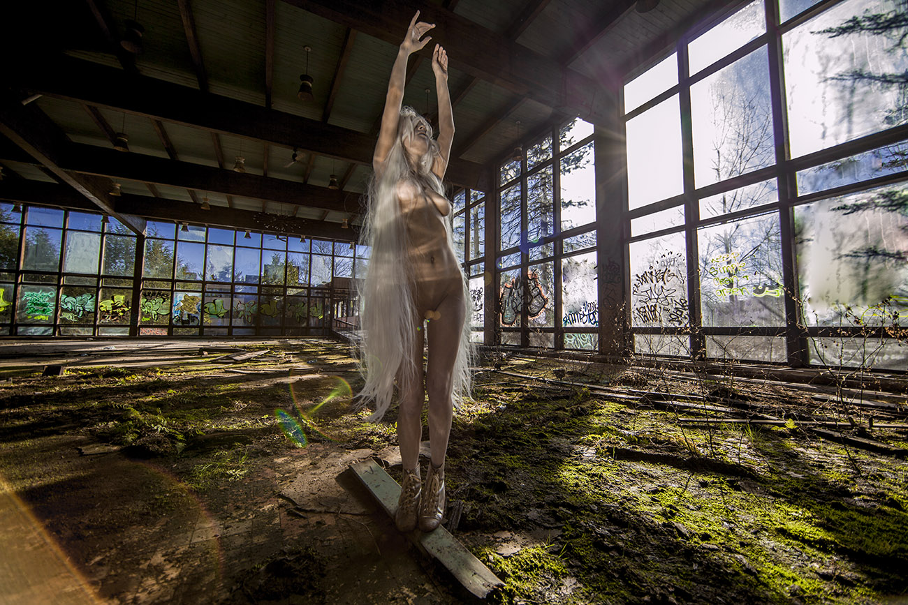 A performer reaches upward in a sunlit, graffiti-marked interior at Grossinger’s Point.